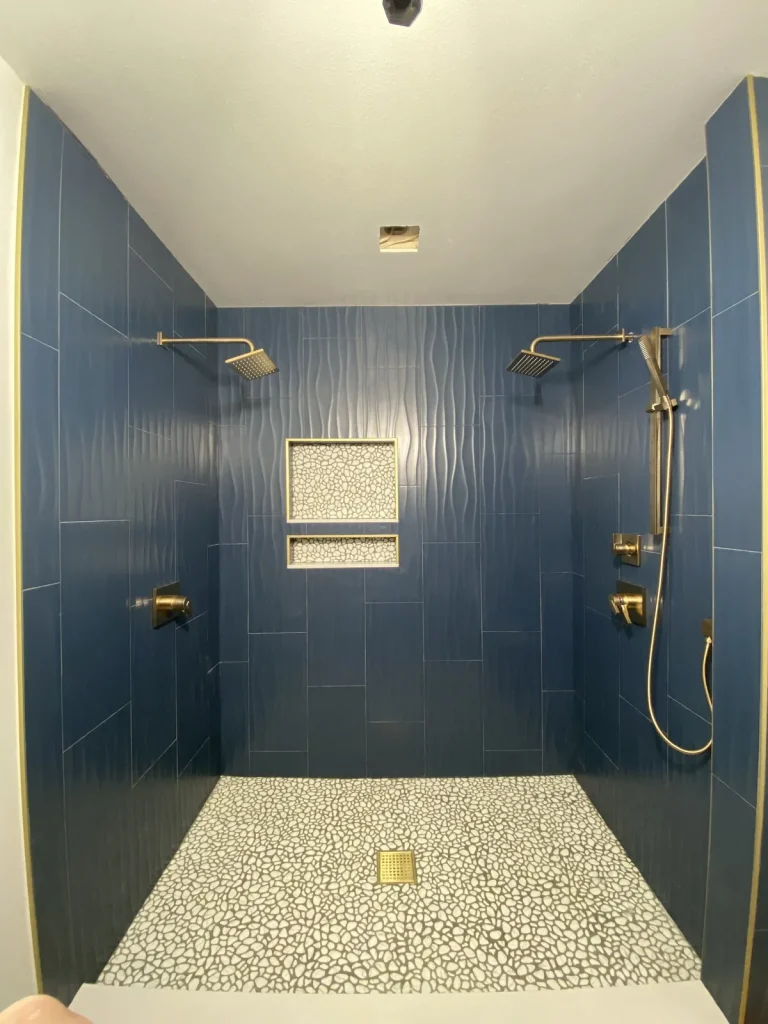 Navy tile walk-in shower with brushed gold fixtures from a completed Panda Plumbing project