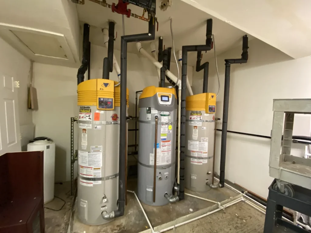 Three power-vent water heaters installed side by side in a mechanical room