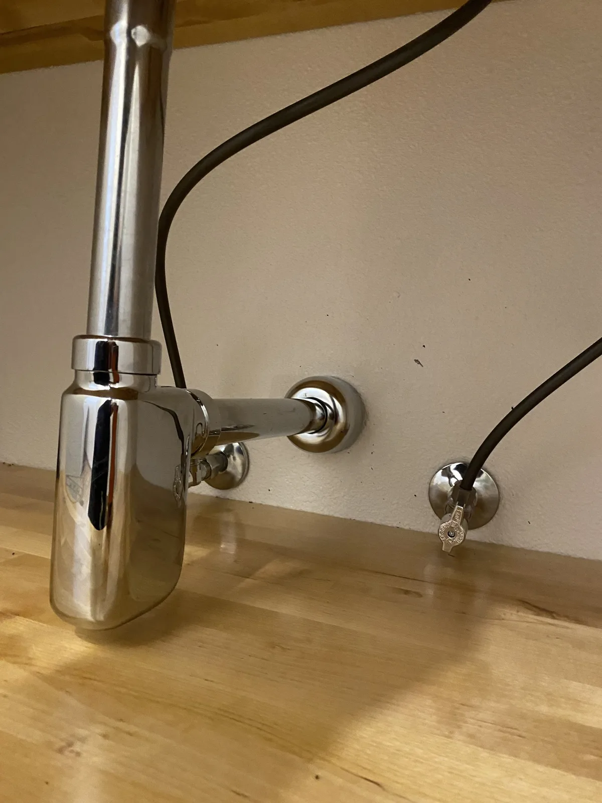 Chrome bottle trap and supply stops under a floating vanity